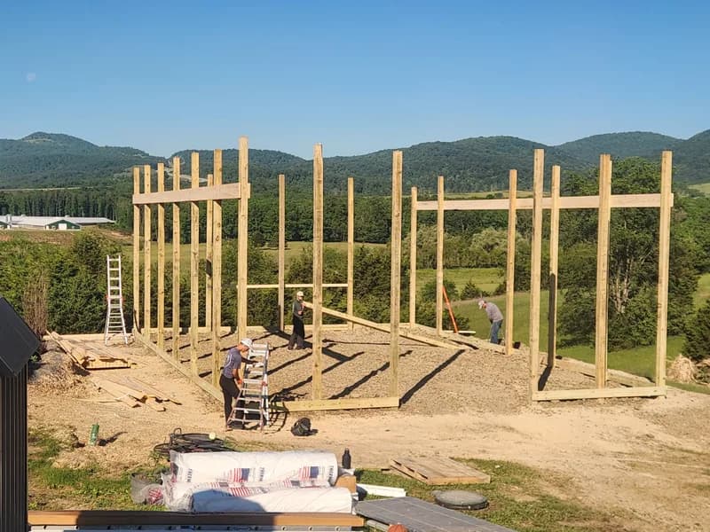Crew raising a post-frame structure against West Virginia mountains