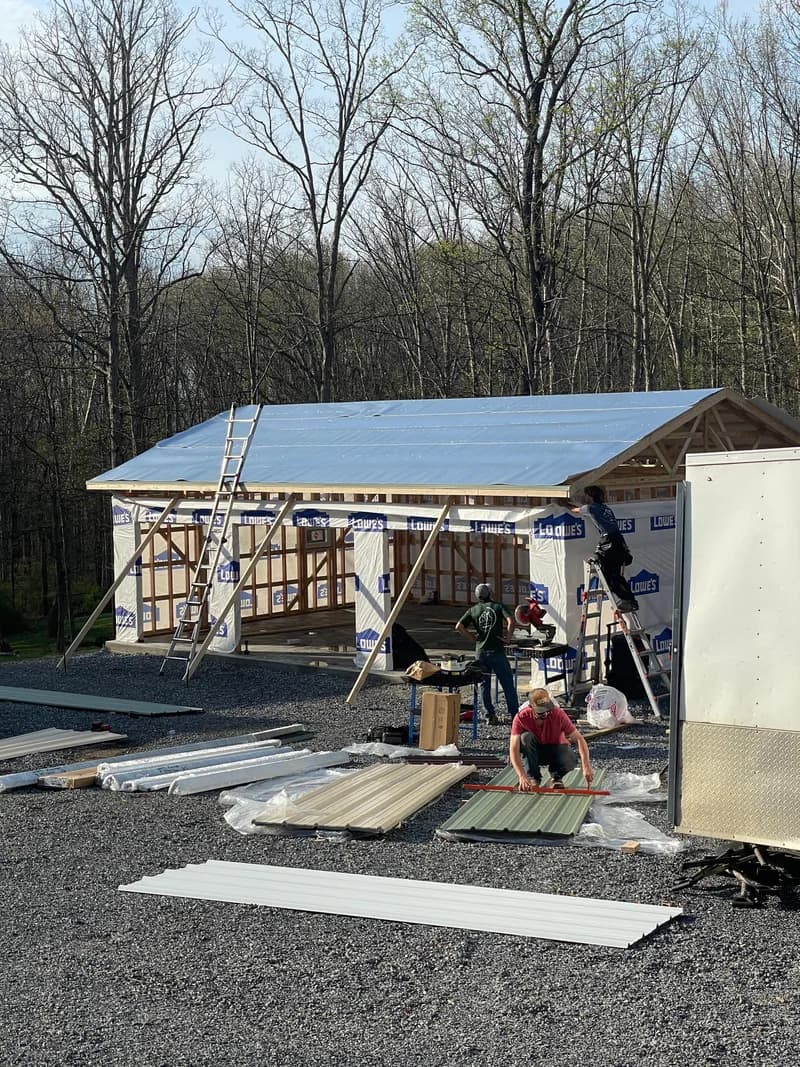 Metal wall panels being installed on a post-frame building